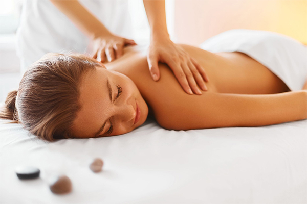 A person's thumbs and fingers applying pressure on someone's back during a home massage.